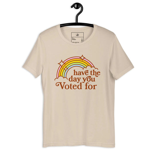 Beige unisex t-shirt with vintage rainbow rainbow and text that says Have The Day You Voted For on a hanger by Rebel Girl Rampage