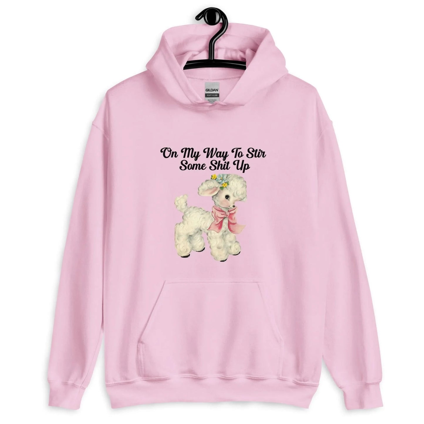 Stir It Up Unisex Pink Hoodie that says, "On my way to stir some shit up" hanging on a hanger with a cute design of a lamb wearing a pink scarf, Rebel Girl Rampage