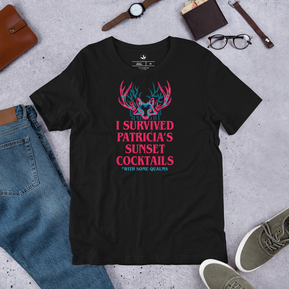 Black unisex t-shirt on a the floor with a psychedelic graphic that says, “I survived Patricia’s Sunset Cocktails” at Rebel Girl Rampage 