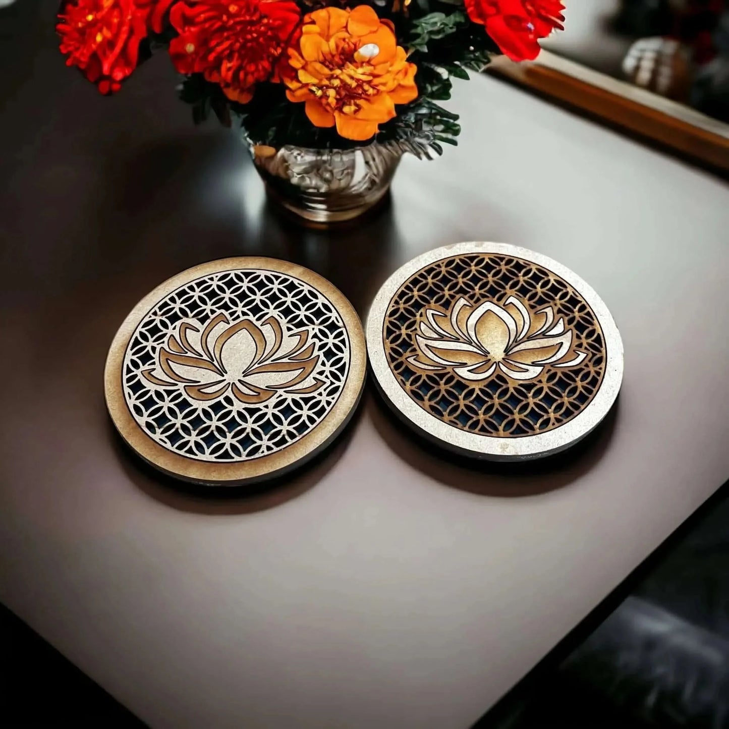 Two small batch boho wooden coasters with lotus flower design on a table with flowers in the background at Rebel Girl Rampage 