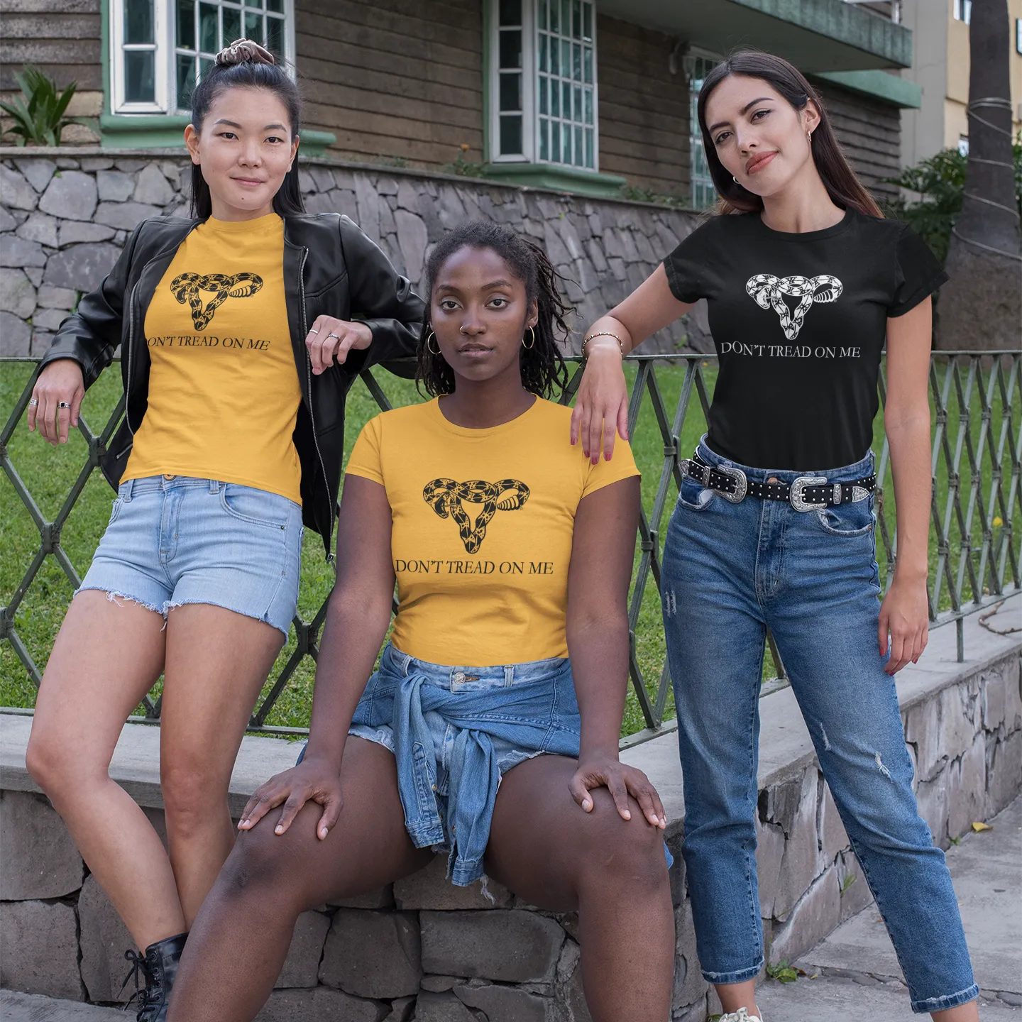 Three people wearing gold or black  t-shirt shirts with an illustration of rattlesnake coiled in the shape of a uterus that says, Don’t Tread On Me supporting abortion rights and women’s reproductive rights, Rebel Girl Rampage, Anne Lesniak