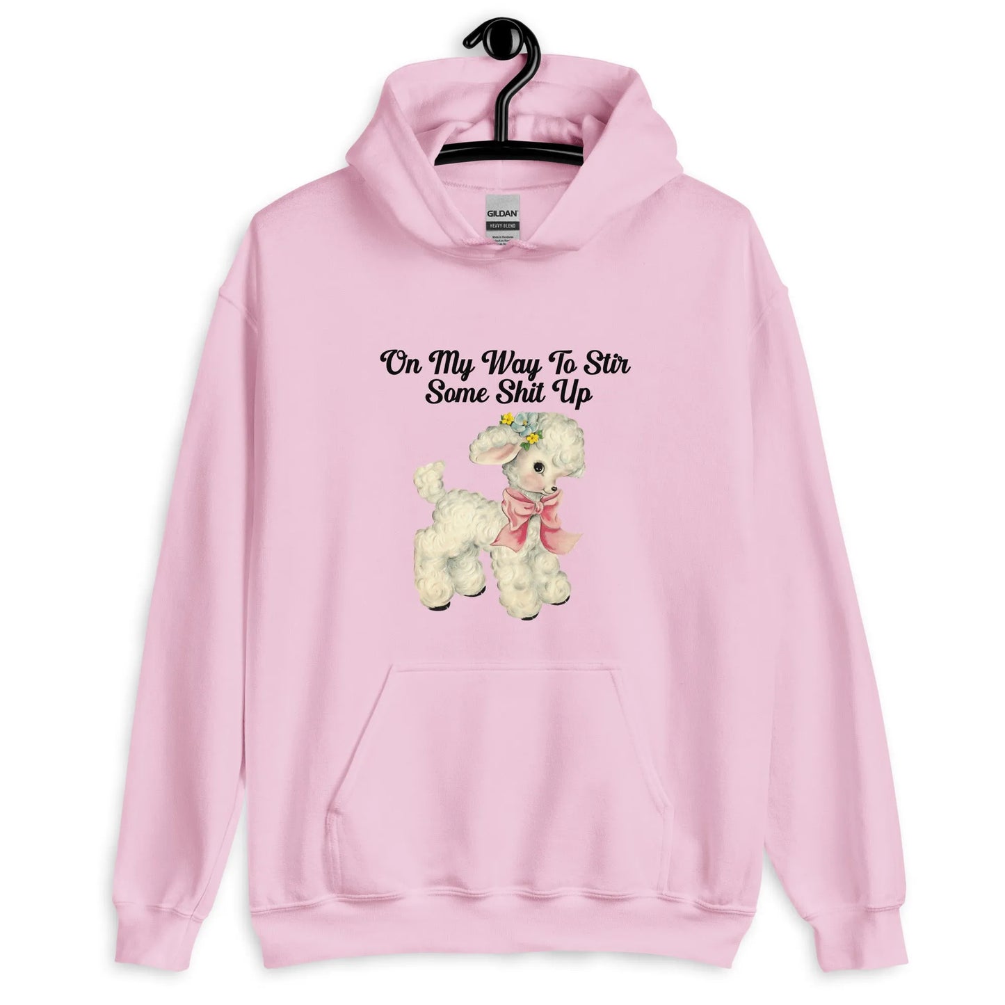 Stir It Up Unisex Pink Hoodie that says, "On my way to stir some shit up" hanging on a hanger with a cute design of a lamb wearing a pink scarf, Rebel Girl Rampage 