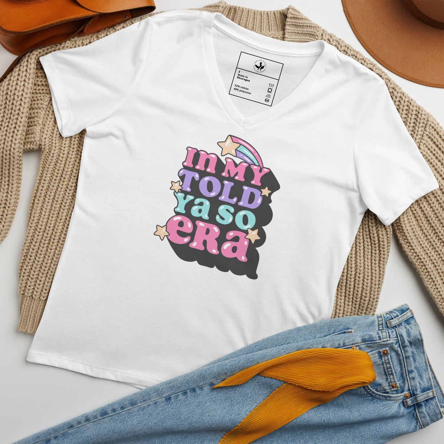 White v-neck t shirt with "In my told ya so era" pink, purple, and light blue graphic lettering with stars surrounded by clothing accessories, speak your mind and tell them, "I told ya so" with a shirt as sassy as you, Rebel Girl Rampage.